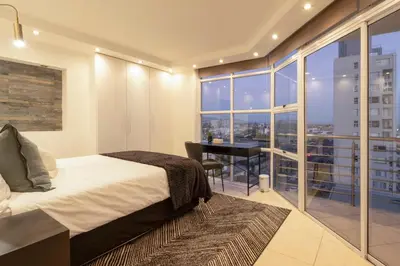 a bedroom with a bed and a desk and a window at Stylish Sunlit Ocean View Oasis! in Cape Town