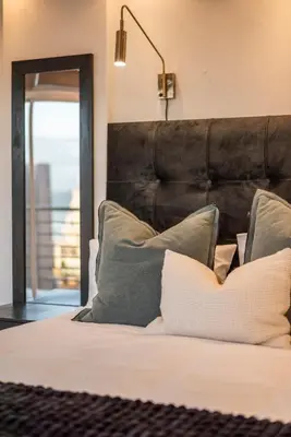 a bed with a black headboard and pillows at Stylish Sunlit Ocean View Oasis! in Cape Town