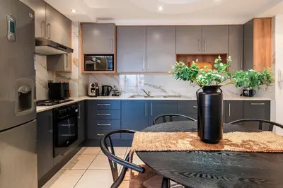 a kitchen with a table with a vase of flowers on it at Stylish Sunlit Ocean View Oasis! in Cape Town