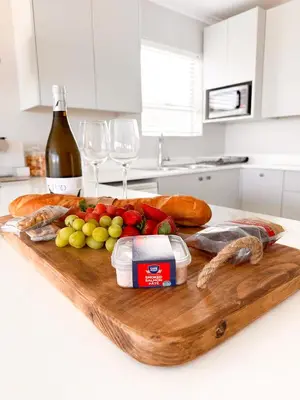 a wooden cutting board with food and wine glasses at Ocean Pearl Hermanus - 5 Bedrooms in Hermanus