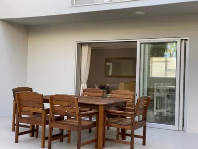 a wooden table and chairs on a patio at Ocean Pearl Hermanus - 5 Bedrooms in Hermanus