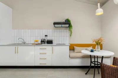 a kitchen with white cabinets and a table at Neighbourgood Franschhoek in Franschhoek