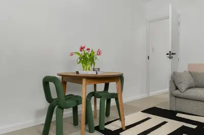 a table with two green chairs and a vase of flowers at Neighbourgood Franschhoek in Franschhoek