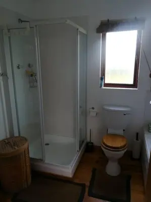 a bathroom with a shower and a toilet and a window at Paradise Beach House in Clareport