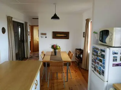 a kitchen and dining room with a table and a refrigerator at Paradise Beach House in Clareport