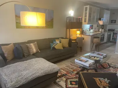 a living room with a couch and a kitchen at Central Stellenbosch Apartment, Dorp Street in Stellenbosch