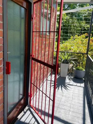 a red door leading to a balcony with plants at Central Stellenbosch Apartment, Dorp Street in Stellenbosch