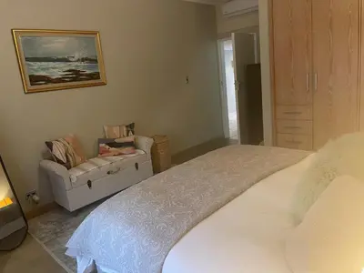 a bedroom with a large bed and a chair at Central Stellenbosch Apartment, Dorp Street in Stellenbosch