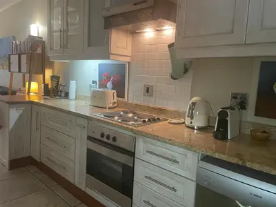 a kitchen with white cabinets and a stove top oven at Central Stellenbosch Apartment, Dorp Street in Stellenbosch