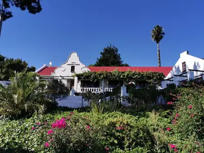 a white house with a red roof and flowers at Somerset Grace Double en-suit in Somerset West