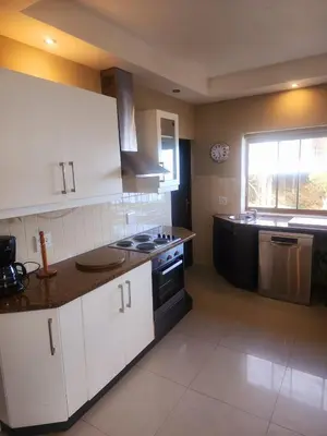 a kitchen with white cabinets and a stove and a window at Bikini Beach Manor in Gordonʼs Bay