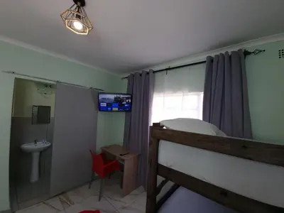 a bedroom with a bed and a sink and a window at Ojong's Guesthouse Kraaifontein - Eikendel in Cape Town