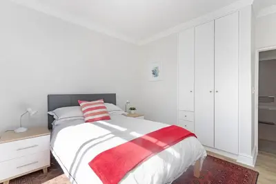 a white bedroom with a bed with a red and white blanket at Sunset Spring Villa in Cape Town