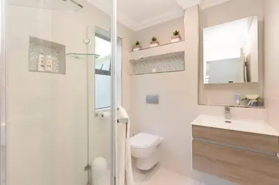 a bathroom with a shower and a toilet and a sink at Sunset Spring Villa in Cape Town