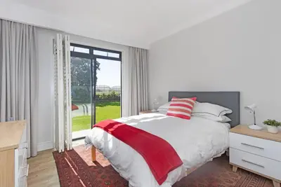 a white bedroom with a bed and a large window at Sunset Spring Villa in Cape Town