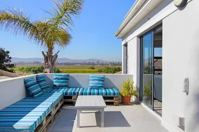 a patio with blue pillows and a bench on a balcony at Sunset Spring Villa in Cape Town