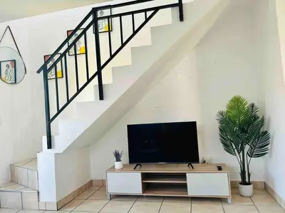 a living room with a tv and a staircase at The Great escape 5 mins away from Blouberg Beach in Cape Town