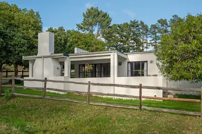a white house with a fence at High Season Farm Luxury Cottages in Hermanus