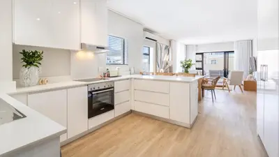 a kitchen with white cabinets and a dining room at The W-Collection Esplanade Hermanus in Hermanus