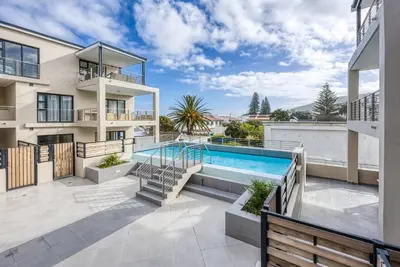 an apartment patio with a swimming pool and a balcony at The W-Collection Esplanade Hermanus in Hermanus