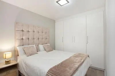 a bedroom with a white bed with a large headboard at Modern 3 Bed Apartment Blouberg in Cape Town