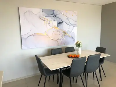 a dining room table with chairs and a painting on the wall at Modern 3 Bed Apartment Blouberg in Cape Town