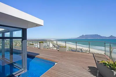a house with a deck with a view of the beach at Modern 3 Bed Apartment Blouberg in Cape Town