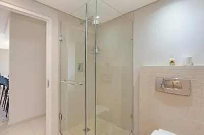 a shower with a glass door in a bathroom at Modern 3 Bed Apartment Blouberg in Cape Town