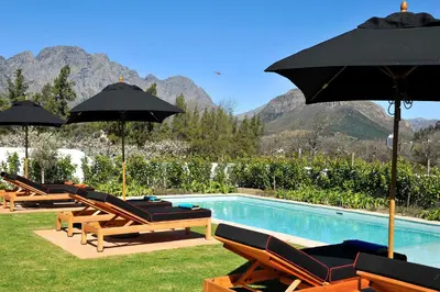 a group of chairs and umbrellas next to a swimming pool at La Clé Village in Franschhoek