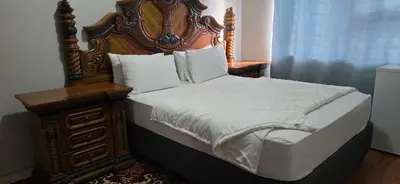 a bed with a wooden headboard next to a dresser at GALAXY BOSTON BELLVILLE in Cape Town