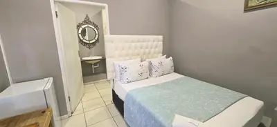 a small bedroom with a bed and a mirror at GALAXY BOSTON BELLVILLE in Cape Town