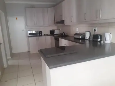 a kitchen with white cabinets and a gray counter top at GALAXY BOSTON BELLVILLE in Cape Town
