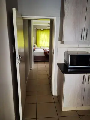 a hallway leading to a kitchen with a bed in a room at GALAXY BOSTON BELLVILLE in Cape Town