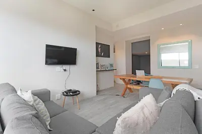 a living room with a gray couch and a table at Sunset Village Atlantic Villa in Cape Town