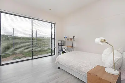 a bedroom with a bed and a large window at Sunset Village Atlantic Villa in Cape Town