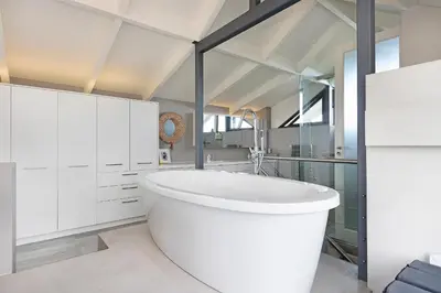 a bathroom with a large white tub in a room at Sunset Village Atlantic Villa in Cape Town