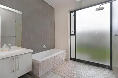 a bathroom with a tub and a sink and a shower at Sunset Village Atlantic Villa in Cape Town