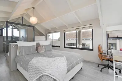 a bedroom with a bed and a desk and windows at Sunset Village Atlantic Villa in Cape Town