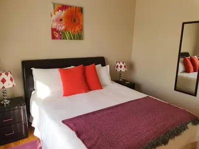 a bedroom with a bed with red and white pillows at Ringwood Villa in Cape Town
