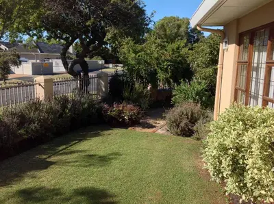 a yard next to a house with a fence at Ringwood Villa in Cape Town