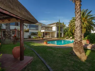 a house with a swimming pool and a palm tree at Villa Vista in Somerset West