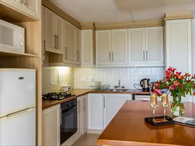 a kitchen with white cabinets and a table with a vase of flowers at Villa Vista in Somerset West