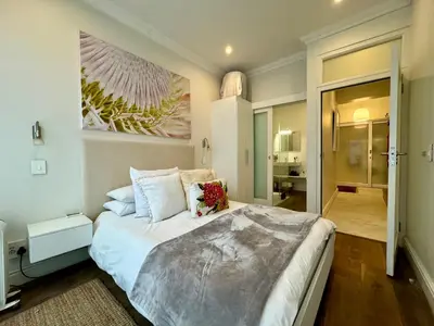 a bedroom with a large bed with a painting on the wall at Tuishuisie in Stellenbosch