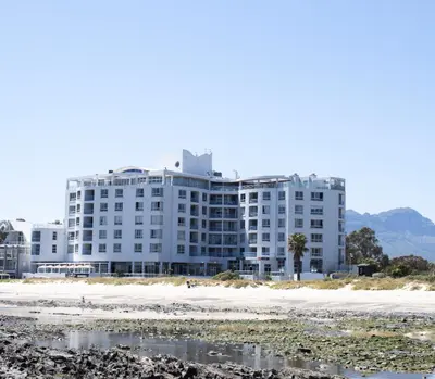 a large white building next to the beach at Ocean Breeze Hotel in Strand
