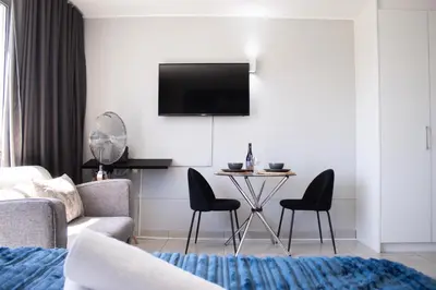 a living room with a couch and a table with chairs at Ocean Breeze Hotel in Strand