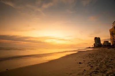 a view of the beach at sunset with buildings at Ocean Breeze Hotel in Strand