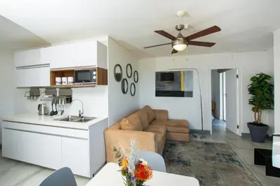 a kitchen and living room with a couch and a ceiling fan at Ocean Breeze Hotel in Strand