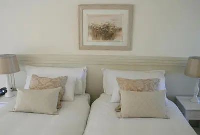 a white bed with pillows and a picture on the wall at Majorca House in Somerset West