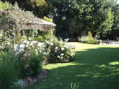 a garden with a gazebo and flowers in a yard at Mooring House in Somerset West
