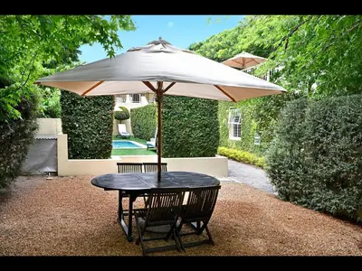a table with an umbrella in a yard at Auberge Daniella in Franschhoek